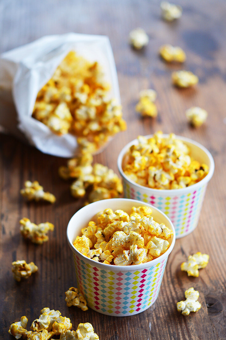 Popcorn mit Curry und Salz in Pappbechern und Papiertüte