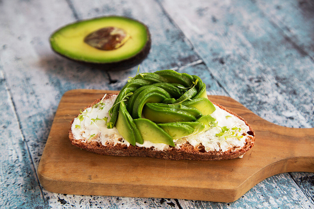 Butter bread with avocado rose and cress, wooden board, indoor, studio