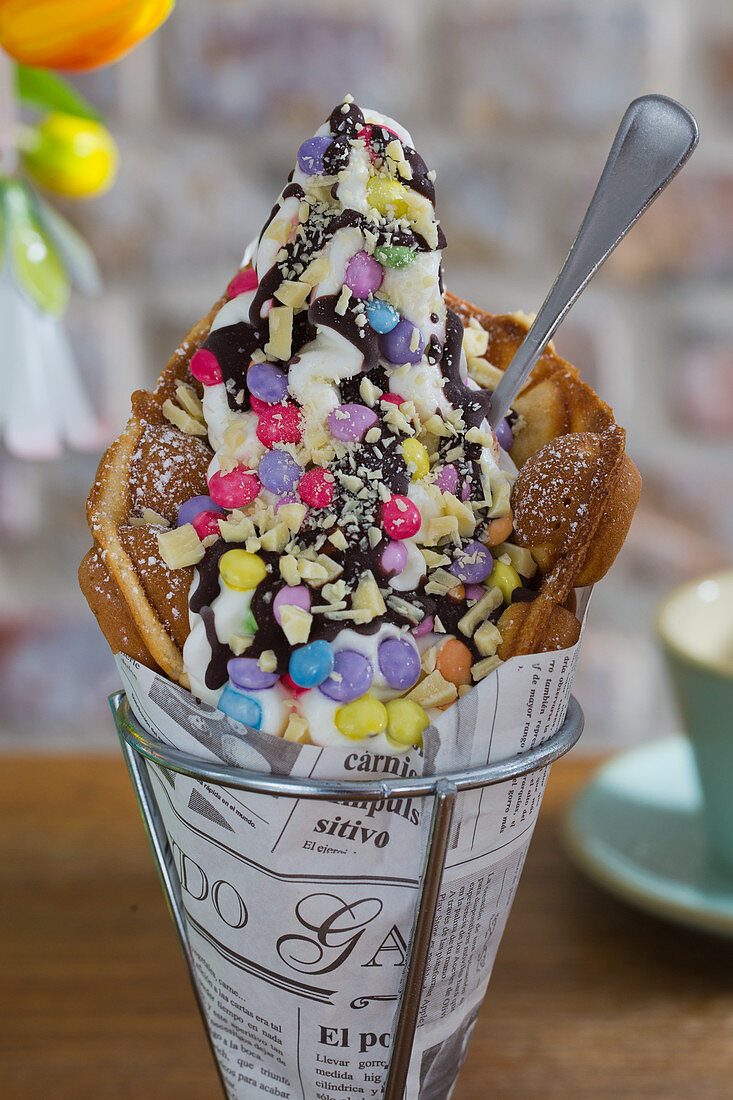 A bubble waffle with cream, Smarties, white chocolate and chocolate sauce