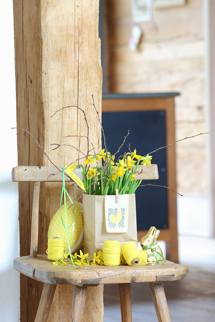 Narcissus in paper bag surrounded by Easter decorations