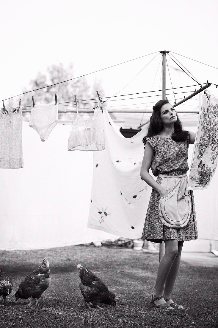 Junge Frau im Sommerkleid mit Schürze beim Wäscheaufhängen (s-w-Aufnahme)