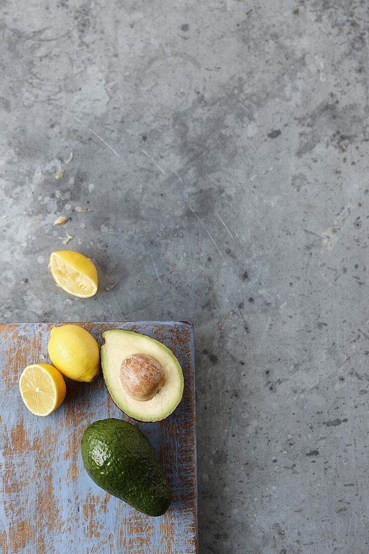 Avocados und Zitronen, ganz und halbiert (Aufsicht)