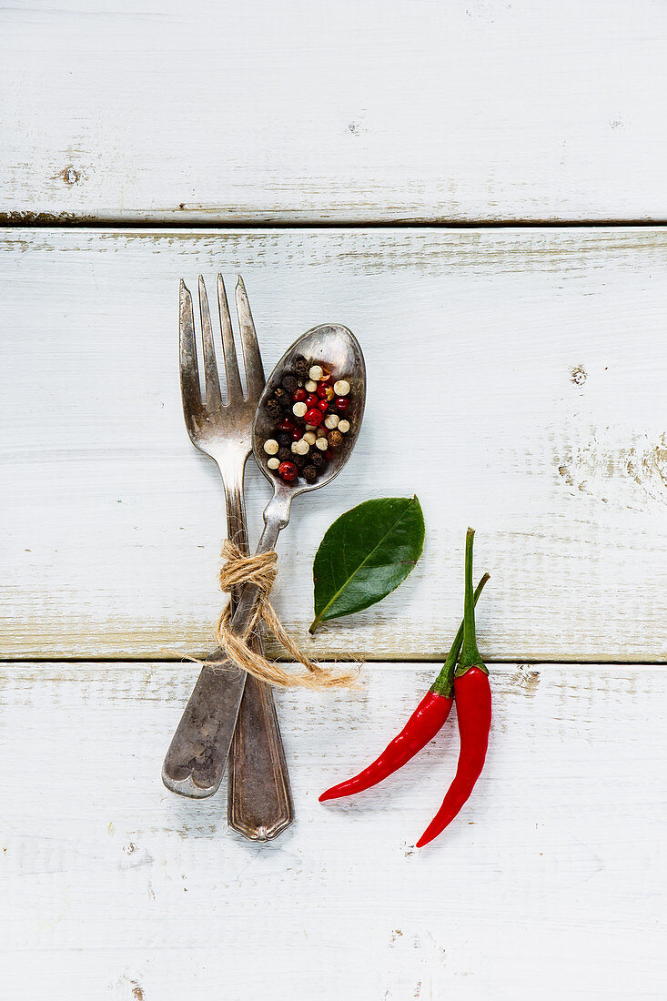 Spices, red hot chili peppers with vintage fork and spoon on white wooden background
