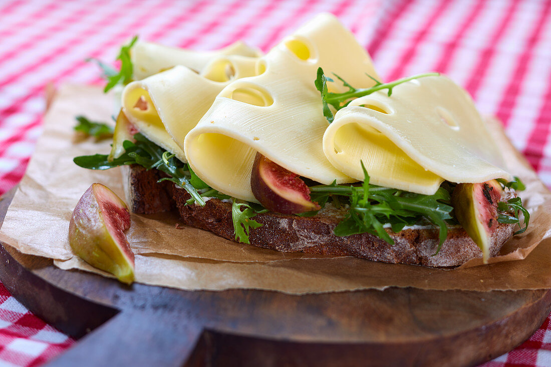 A slice of crusty bread topped with gouda, figs and rocket