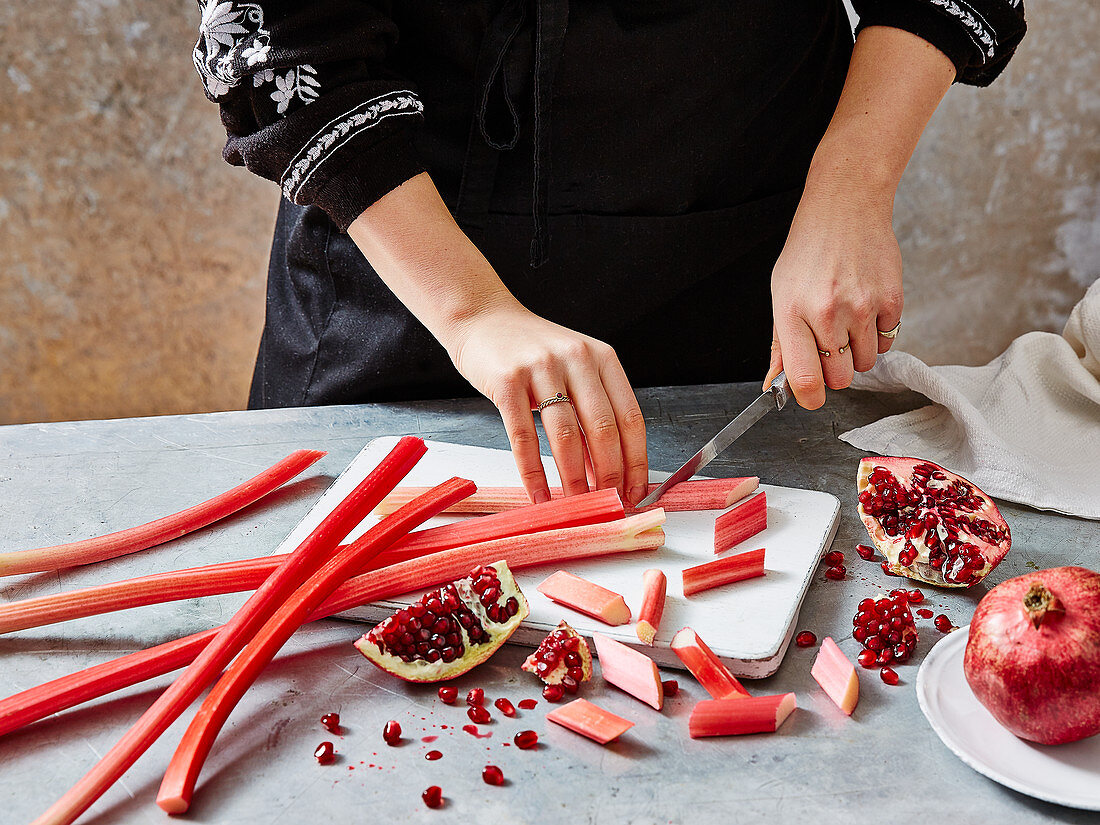 A woman preparing rhubarb and pomegranate