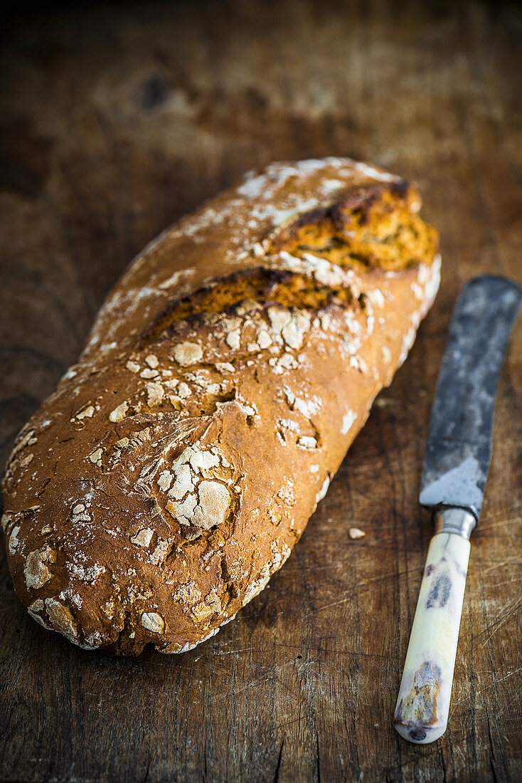 Twice-baked bread with a knife on a wooden surface