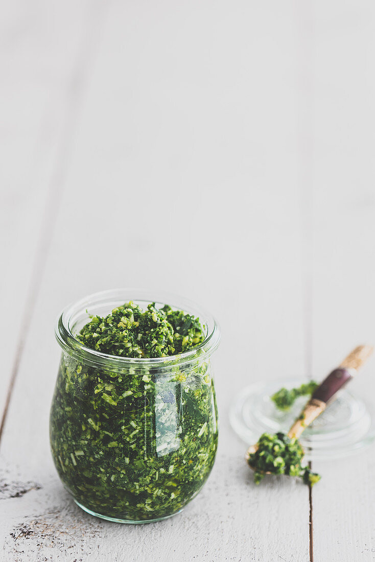 Green kale pesto in a jar and on a spoon