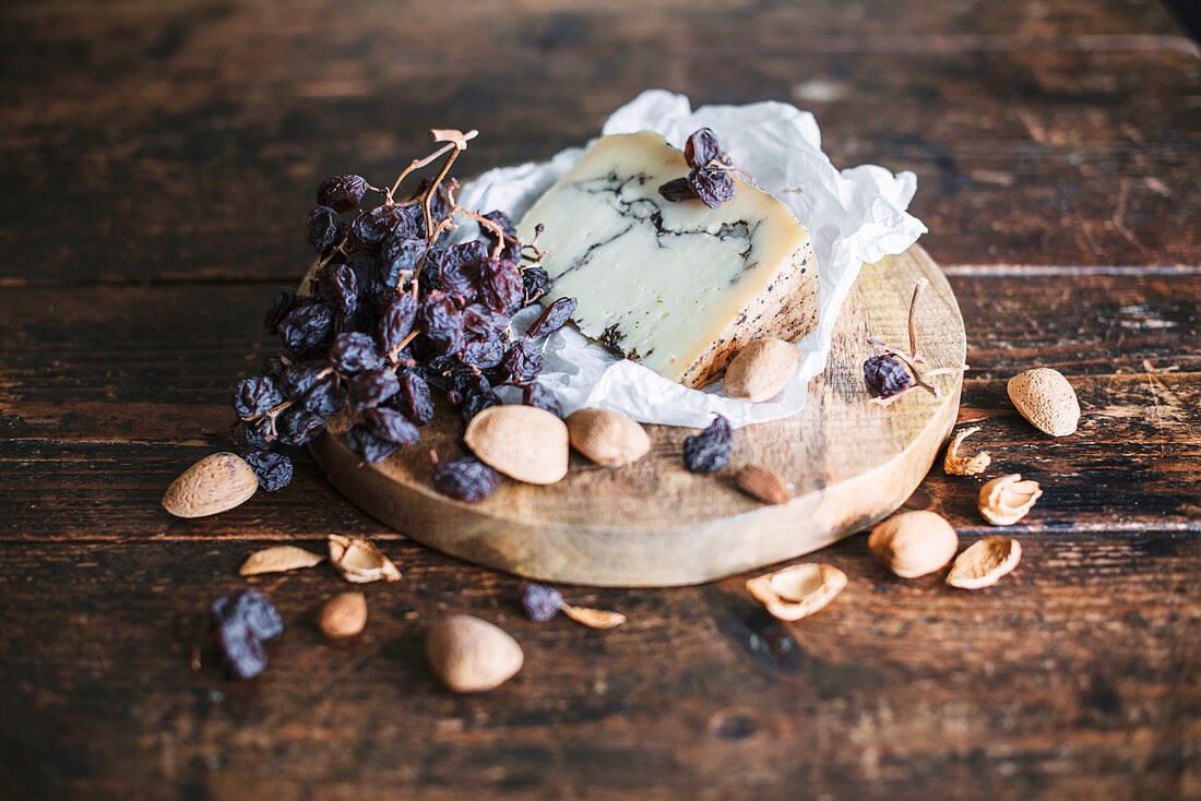 Blue cheese, dried grapes and almonds on a wooden plate
