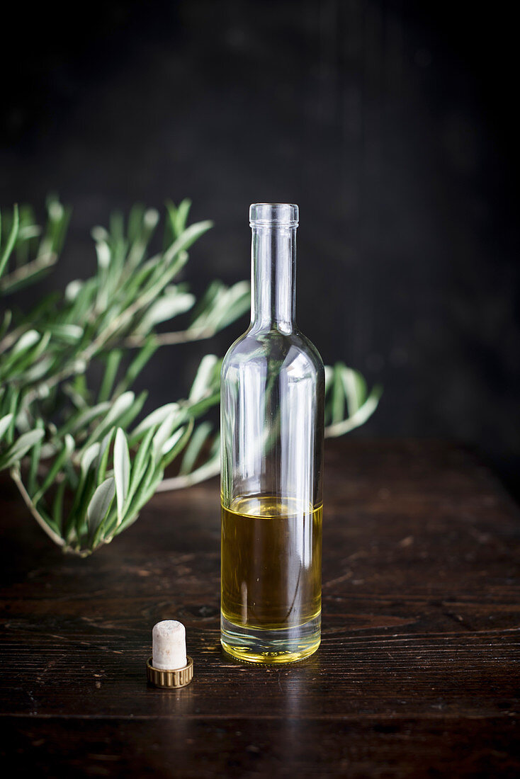 Olive oil in a bottle in front of an olive branch