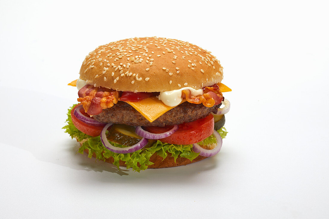 A hamburger with bacon and cheese against a white surface