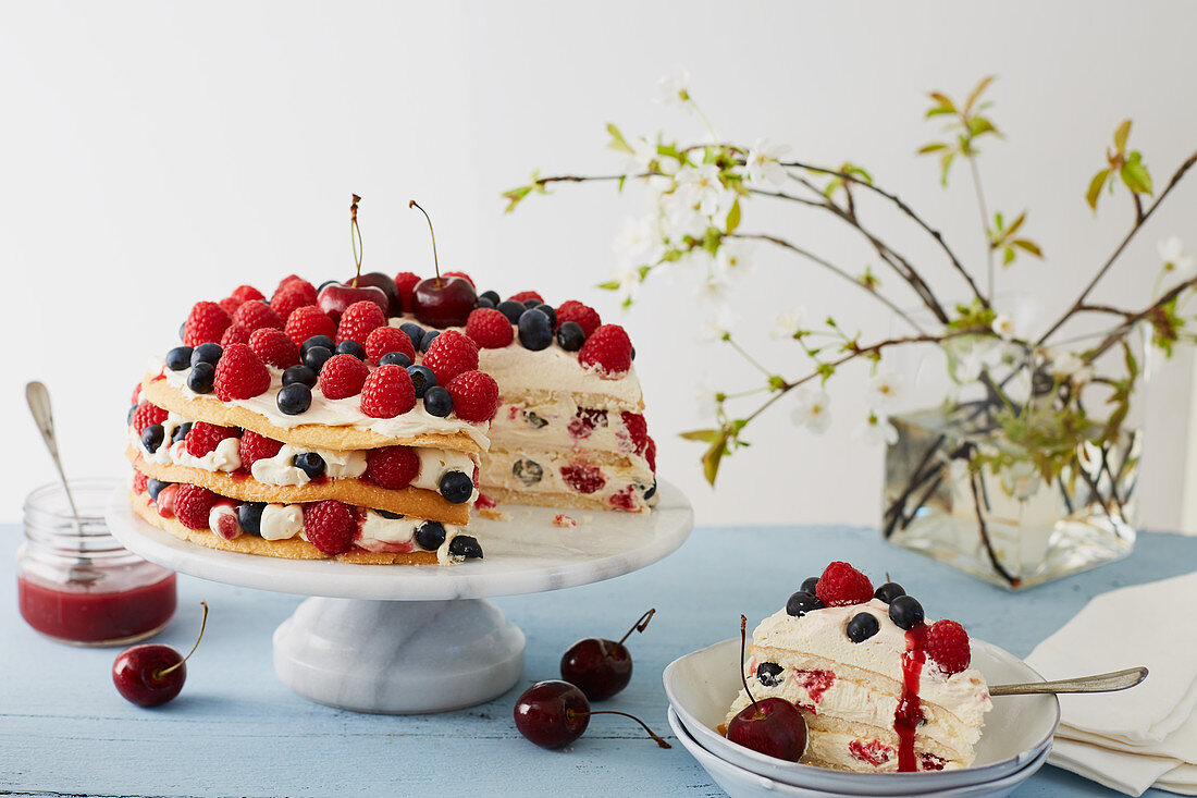 A summery layer cake with berries and cherries, sliced