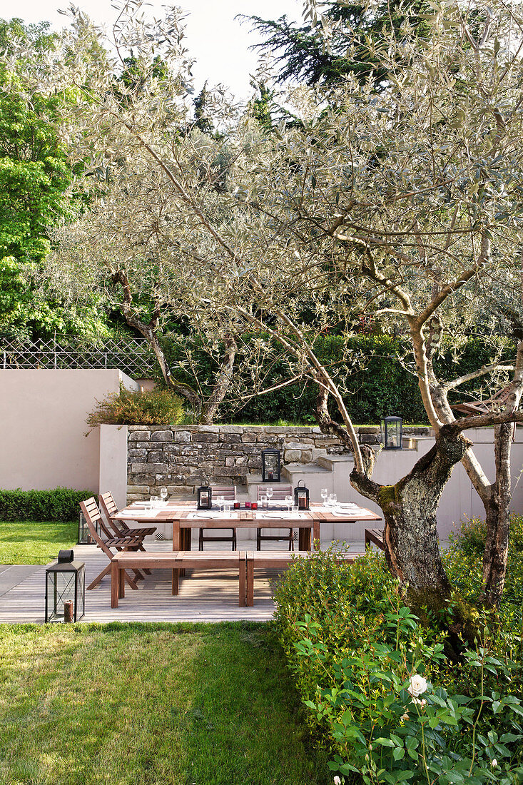 Gedeckter Tisch mit Stühlen und Bänken im mediterranen Garten