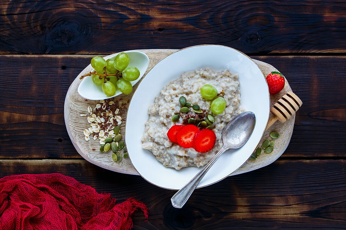 Close up of Homemade oatmeal porridge with berries and seeds in bowl on dark rustic background