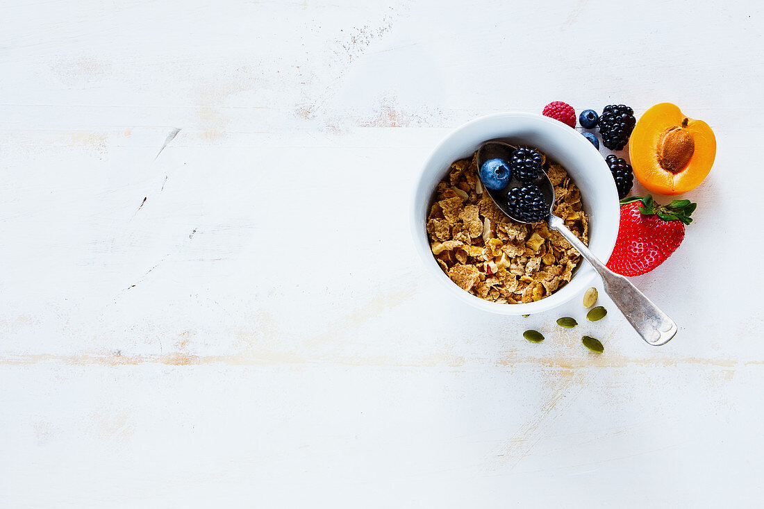 White breakfast bowl of tasty homemade granola, fresh berries and fruits on rustic background