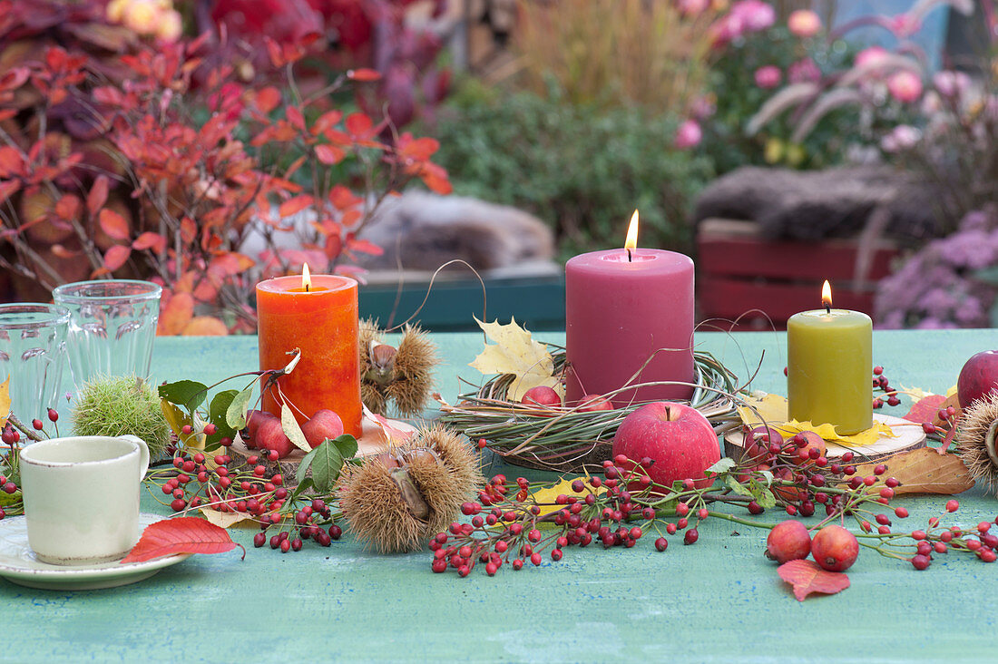 Herbstliche Tischdekoration mit Kerzen, Äpfeln und Hagebutten