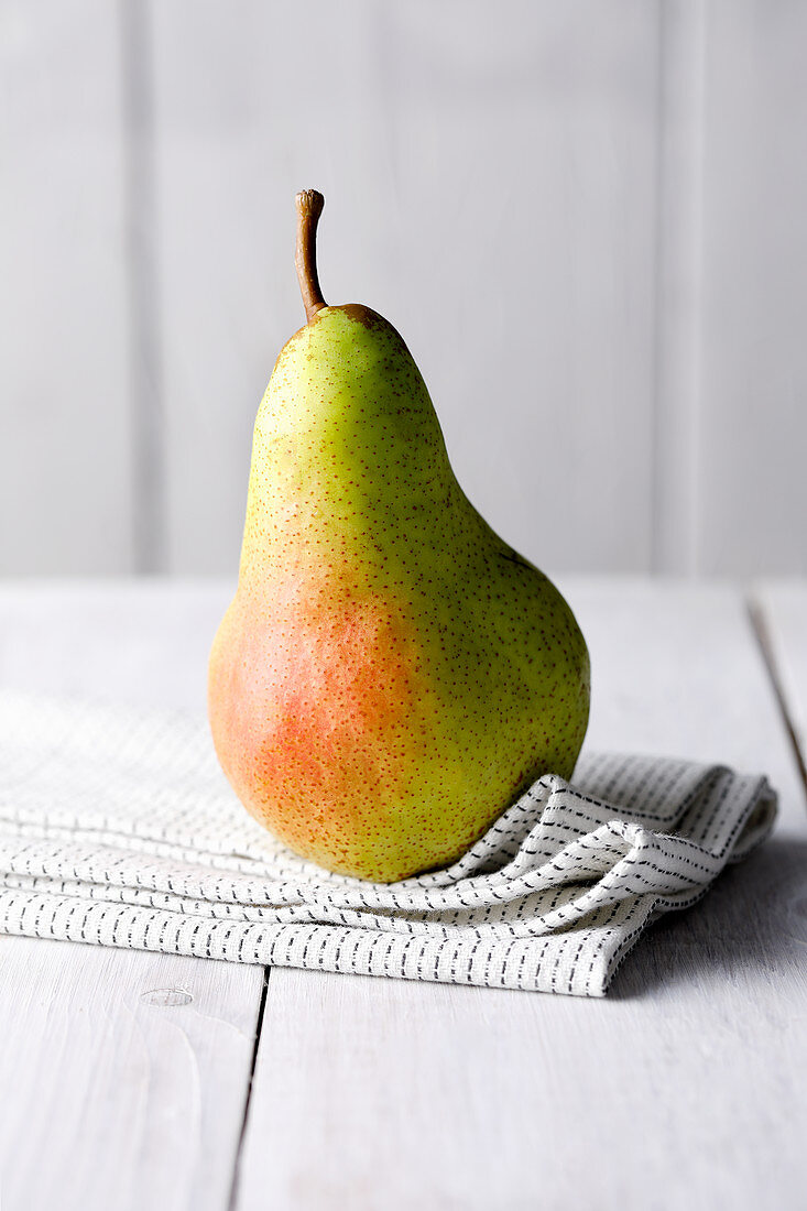 A green and red pear on a cloth napkin