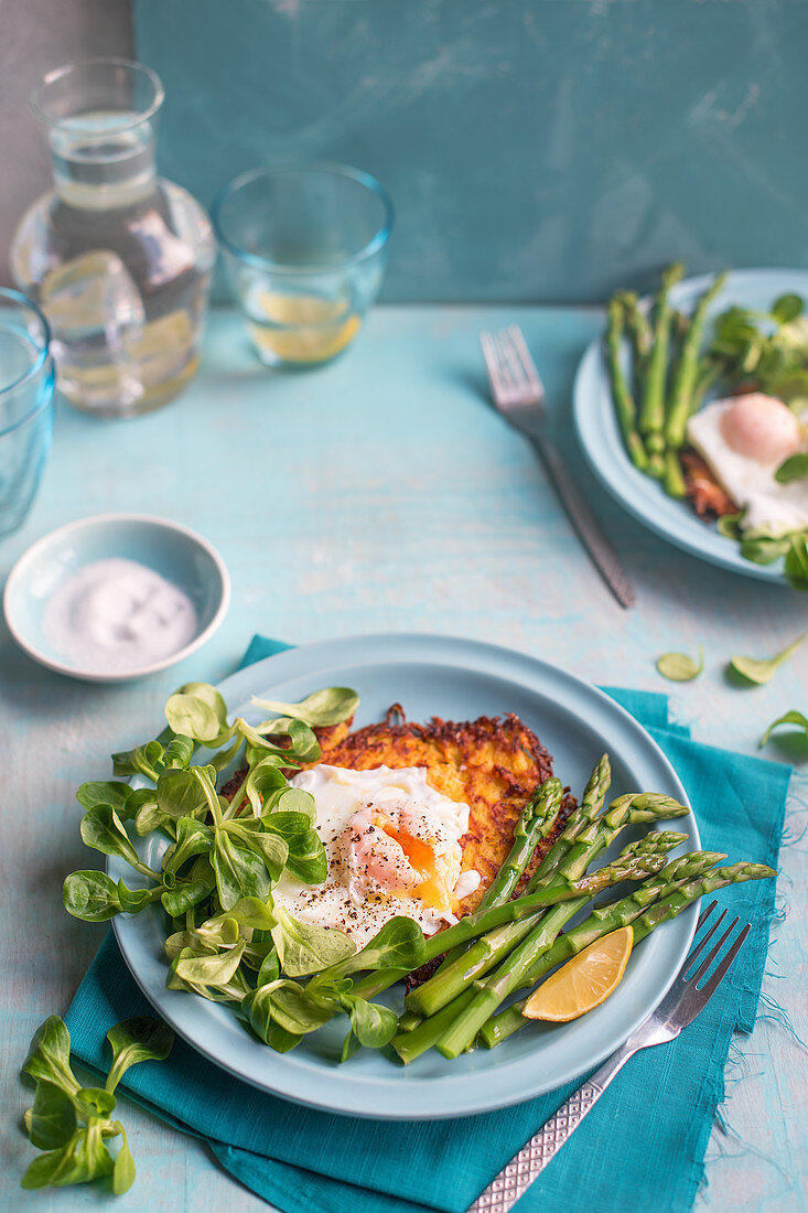 Kartoffelpuffer serviert mit grünem Spargel, Feldsalat und pochiertem Ei