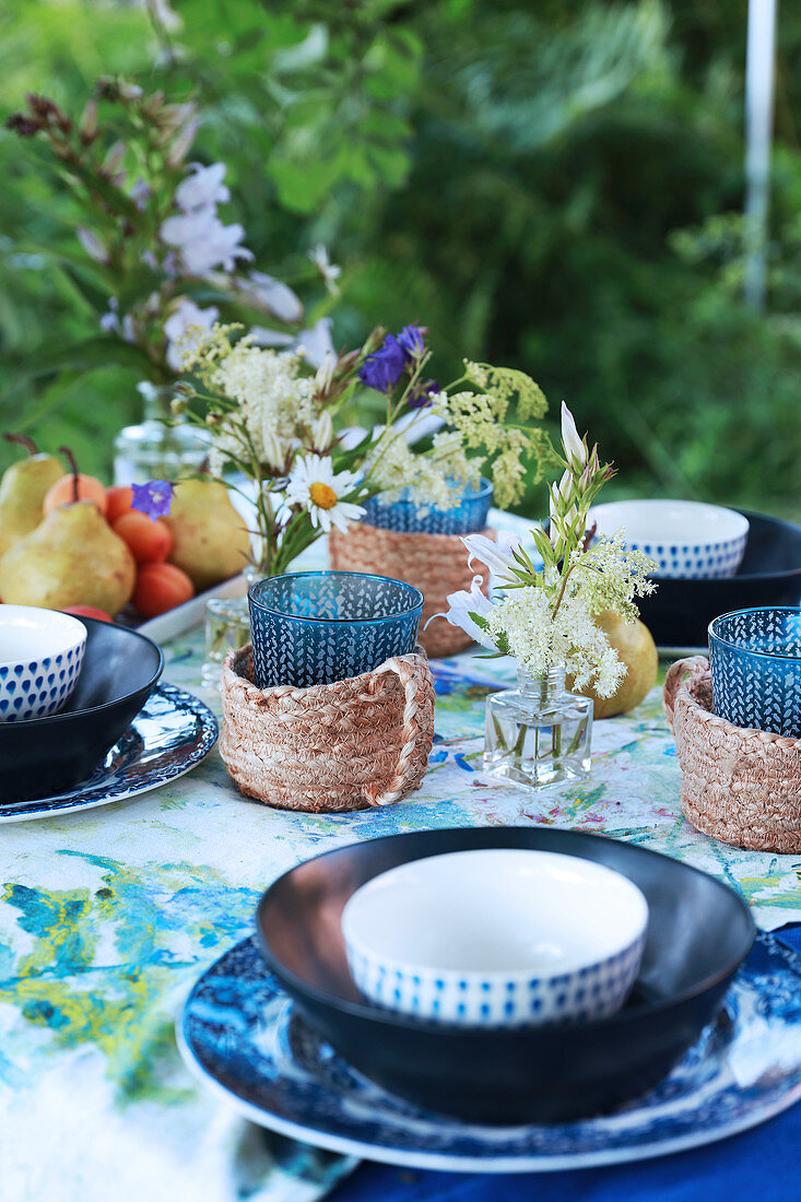 Gedeckter Tisch in Blautönen und mit Bast-Becherhalter im Garten