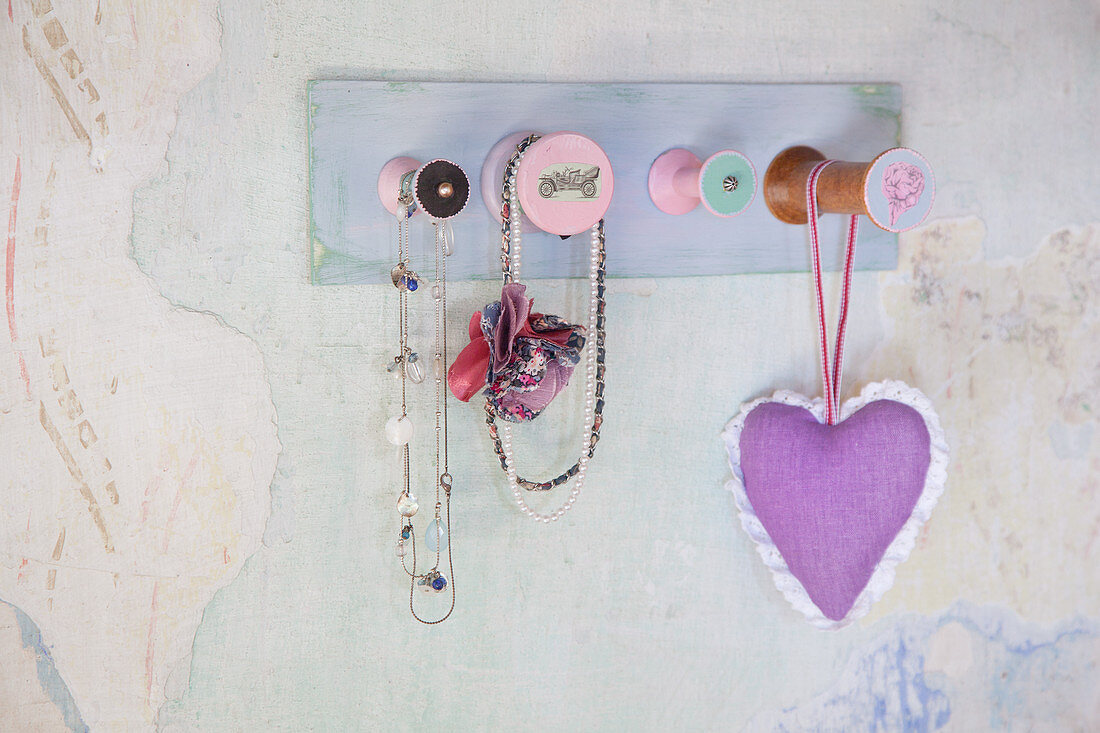 Coat rack made from yarn reels mounted on wall with peeling paint