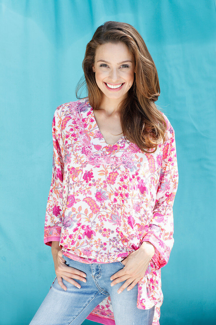 A brunette woman wearing a tunic blouse with a floral pattern