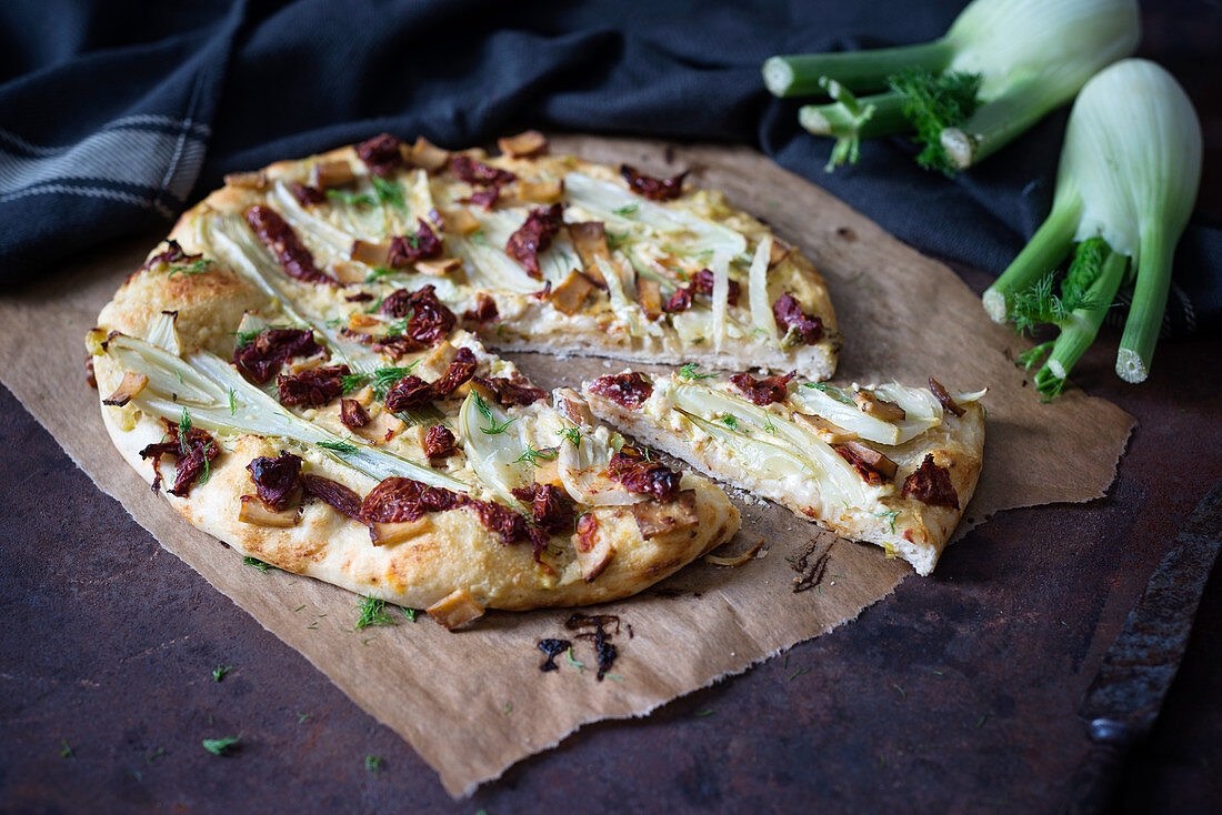 A pizza with fennel, dried tomatoes and smoked tofu (vegan)