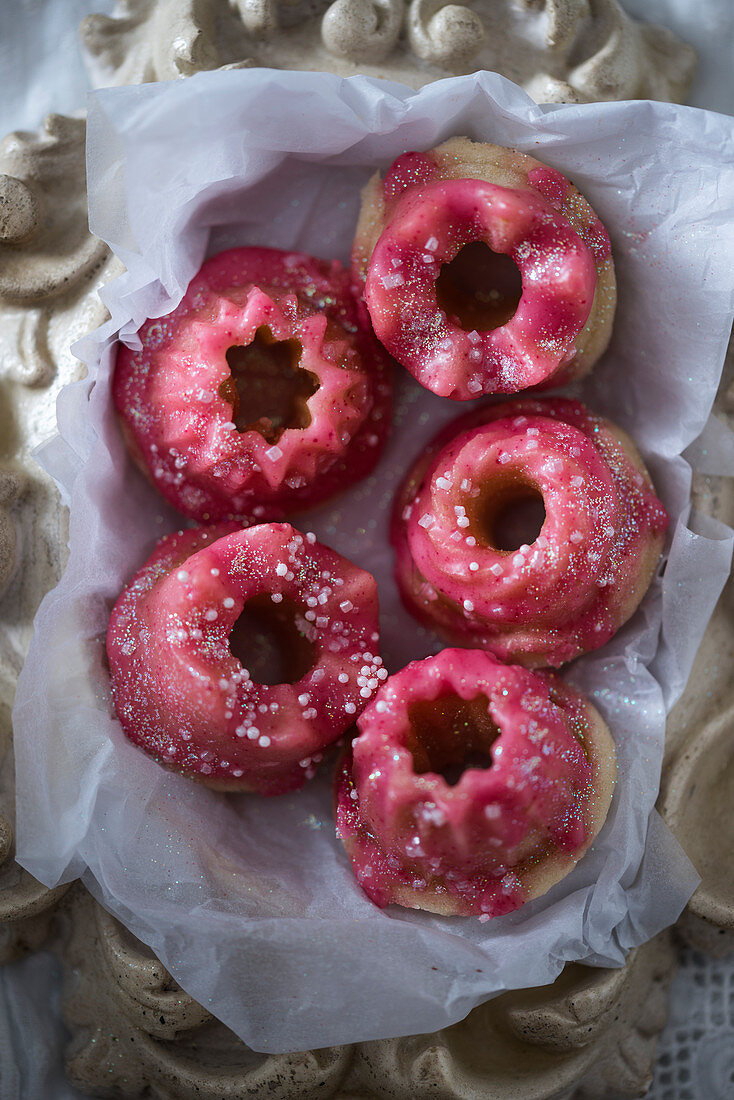 Mini gugelhupfs decorated with pink frosting and edible glitter