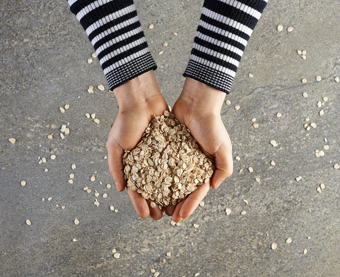 Hands holding rolled oats