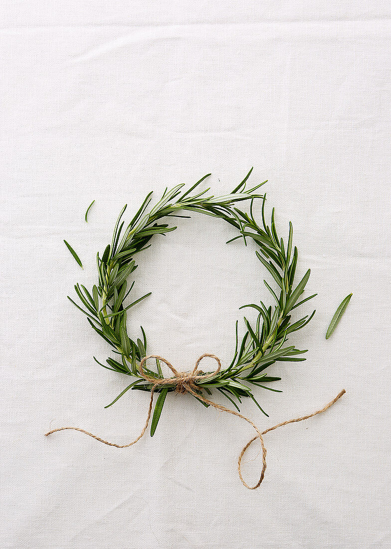 A wreath of rosemary sprigs against a white background