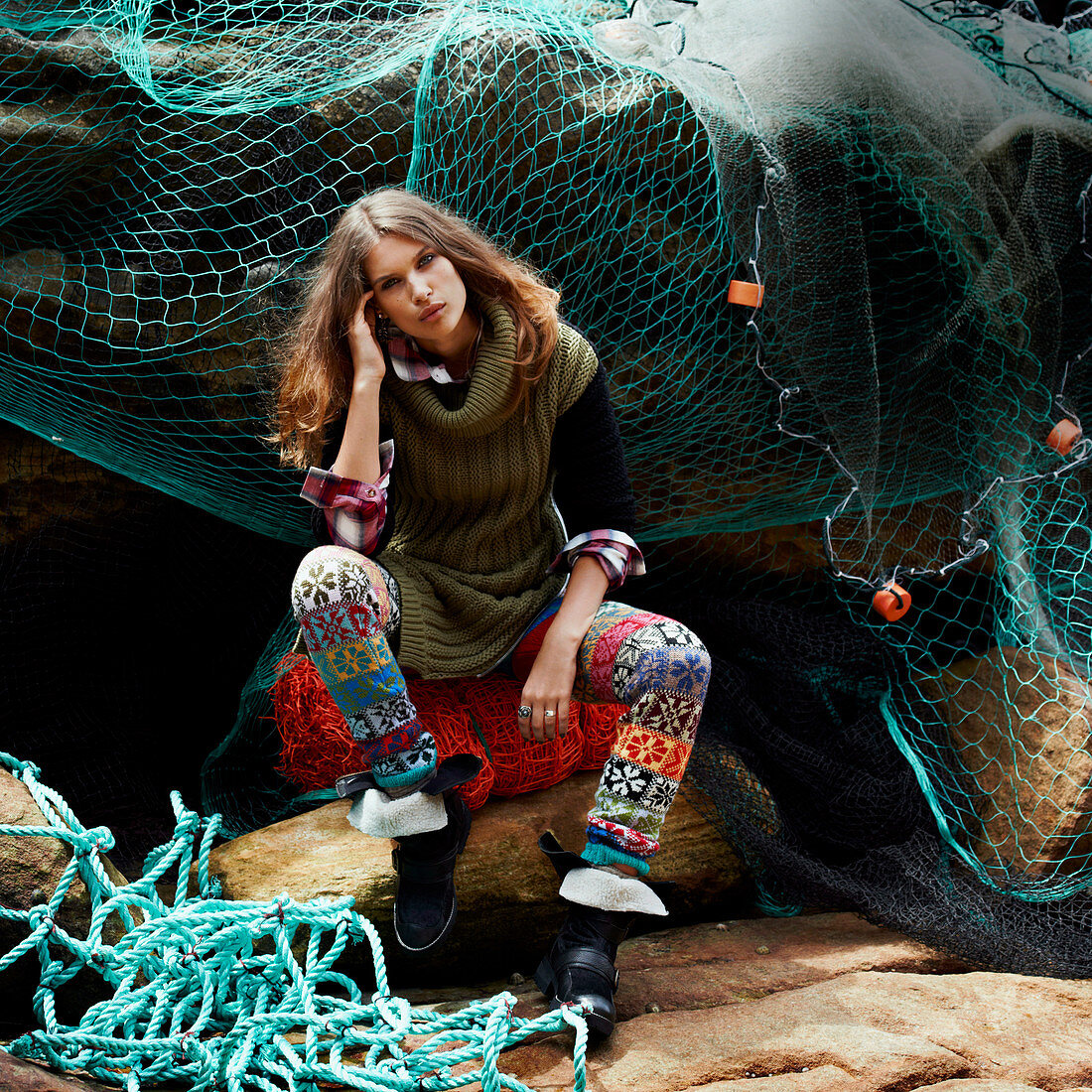 Brünette Frau in gestricktem Longpulli und Leggins vor Fischernetz