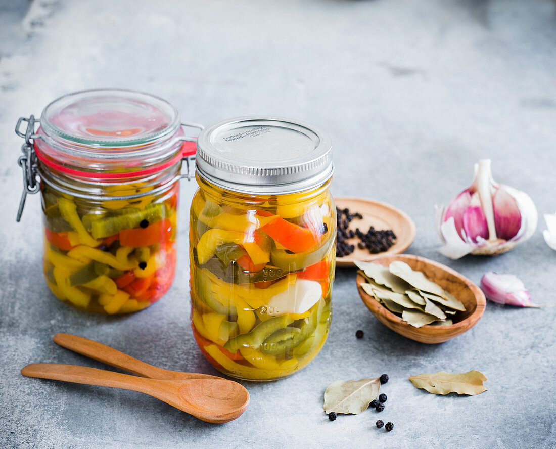 Pickled peppers in preserving jars with various ingredients