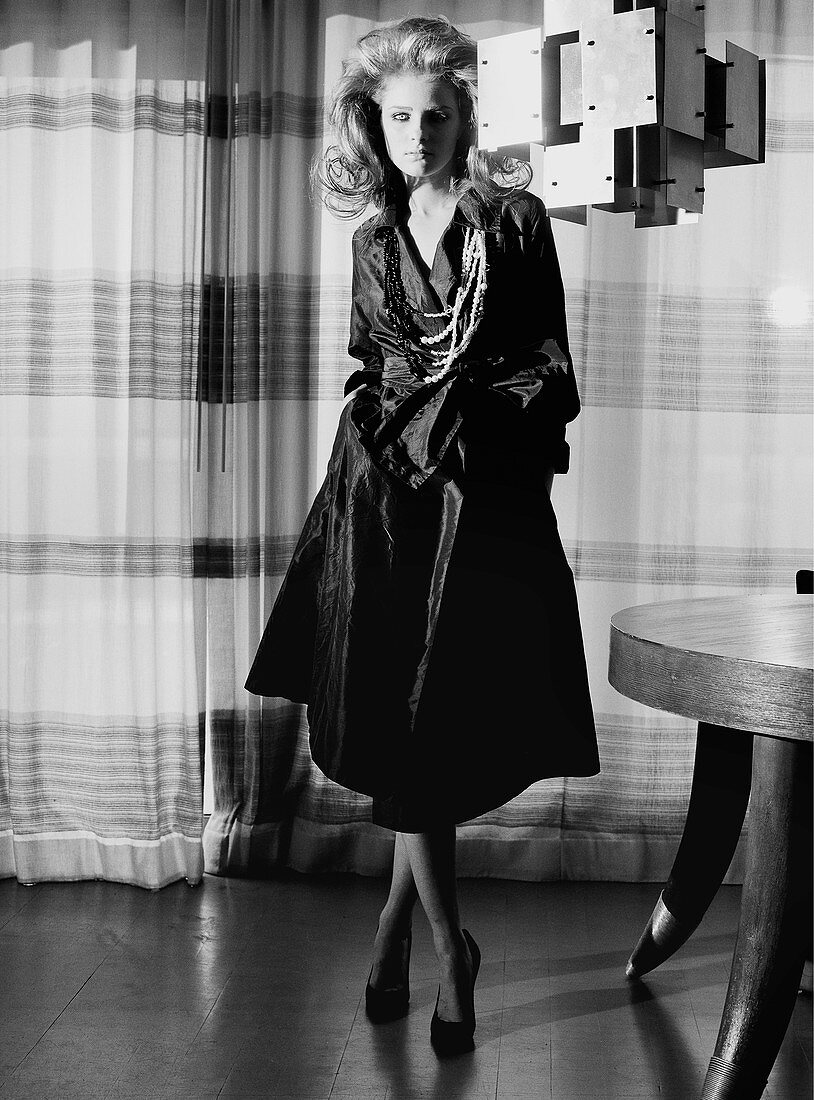 A young woman wearing an elegant, black trench coat (black-and-white shot)