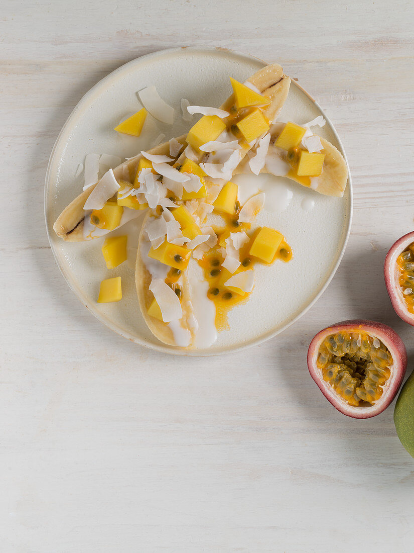 Halved bananas with mango, passion fruit and coconut