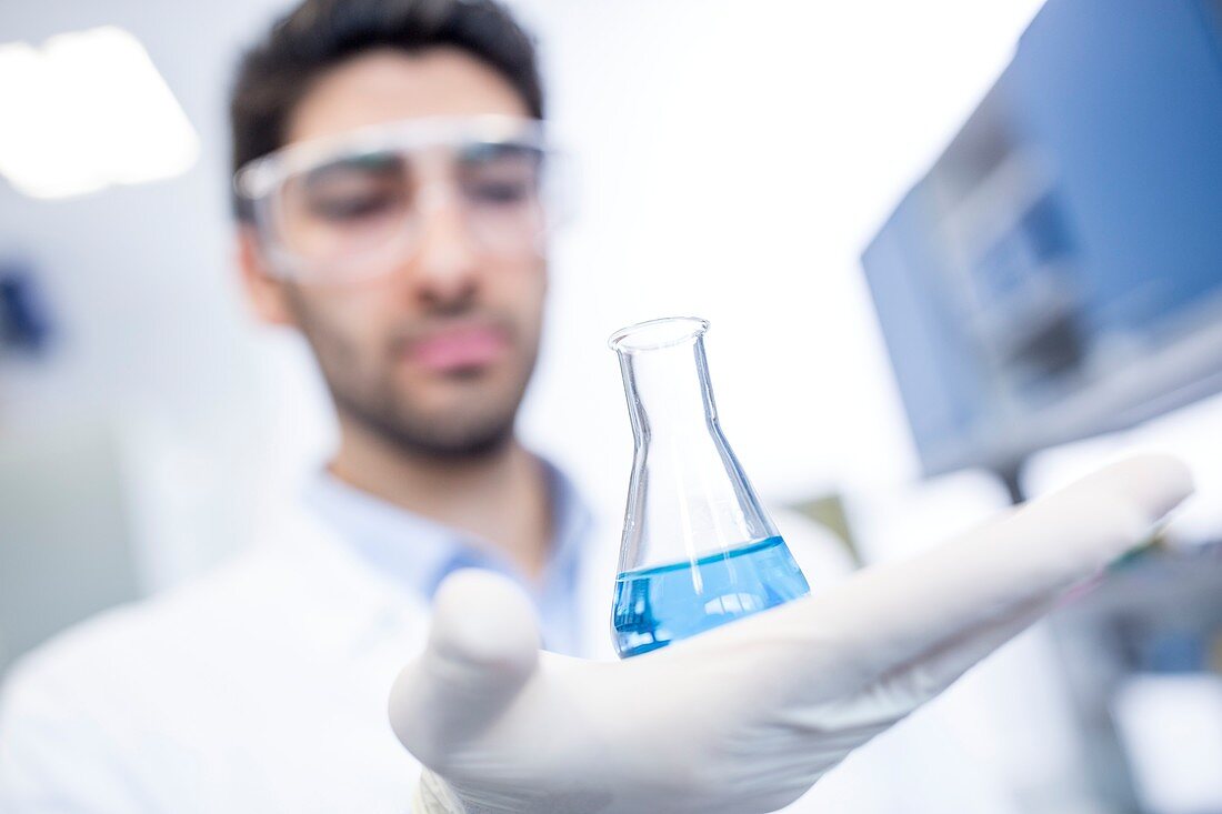 Lab assistant holding chemical flask