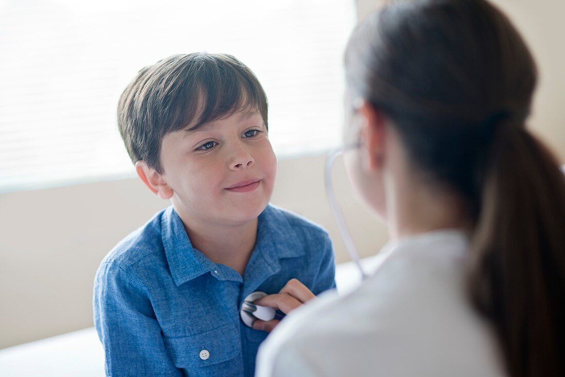 Boy looking toward nurse using stethoscope