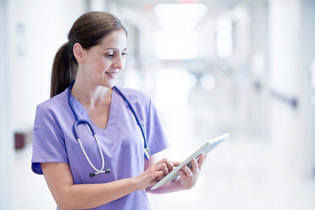 Nurse wearing purple uniform using digital tablet
