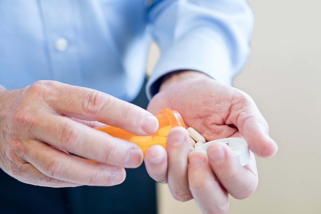 Man pouring pills onto hand from bottle