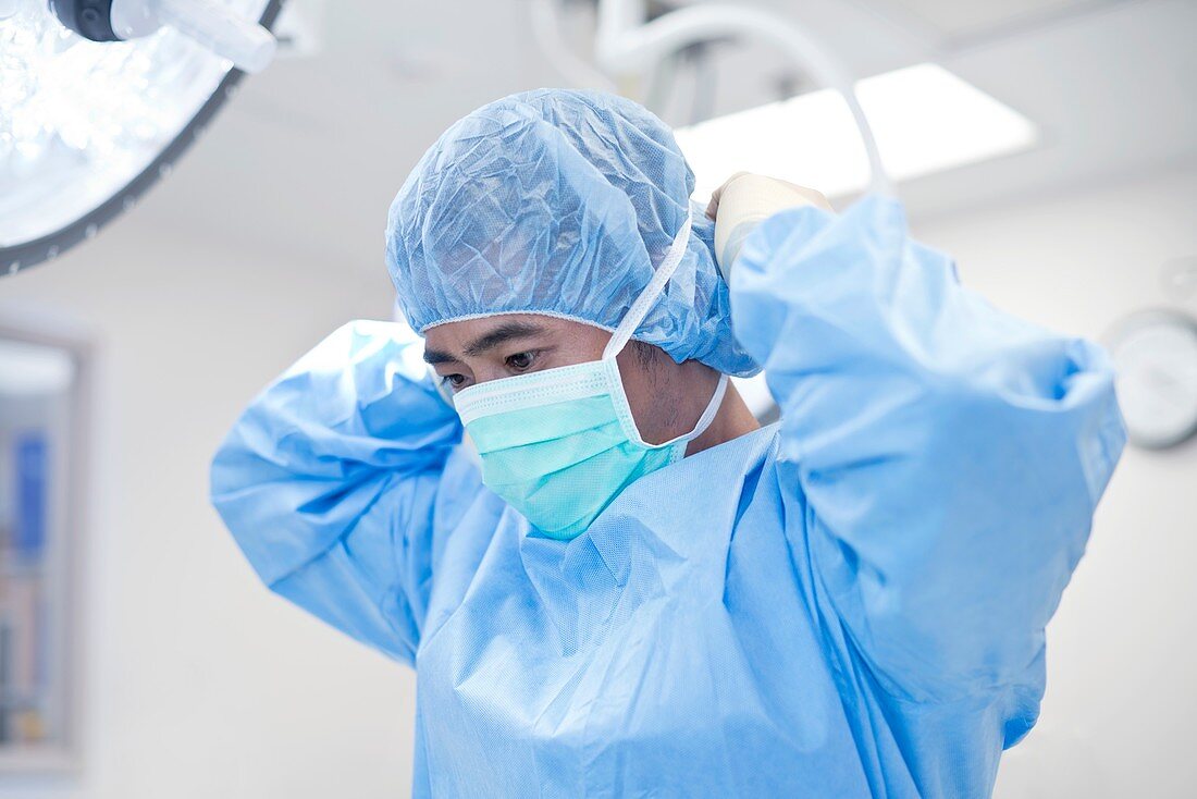 Male surgeon putting on surgical mask