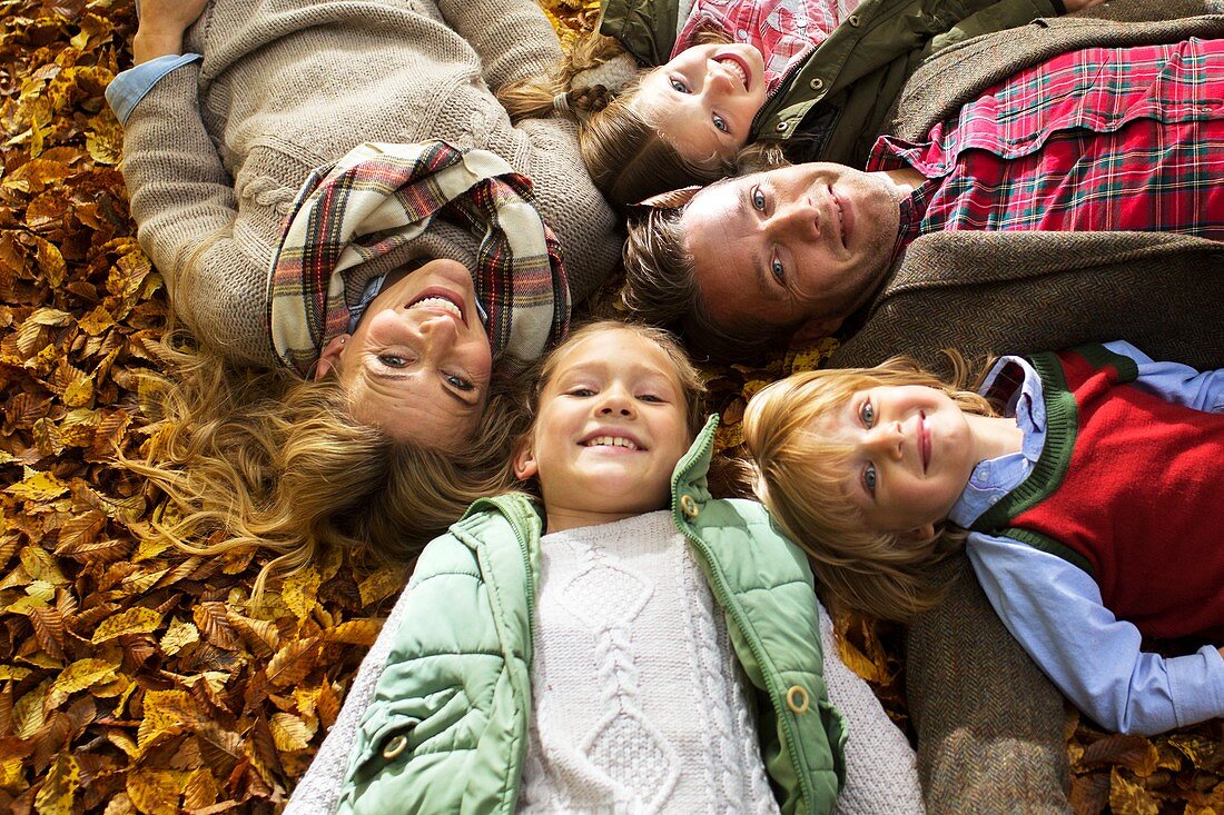 Family lying down on Autumn leaves