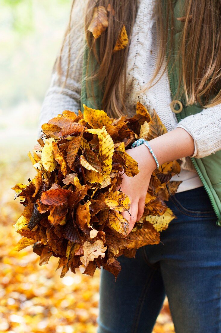 Girl holding a pile of Autumn leaves