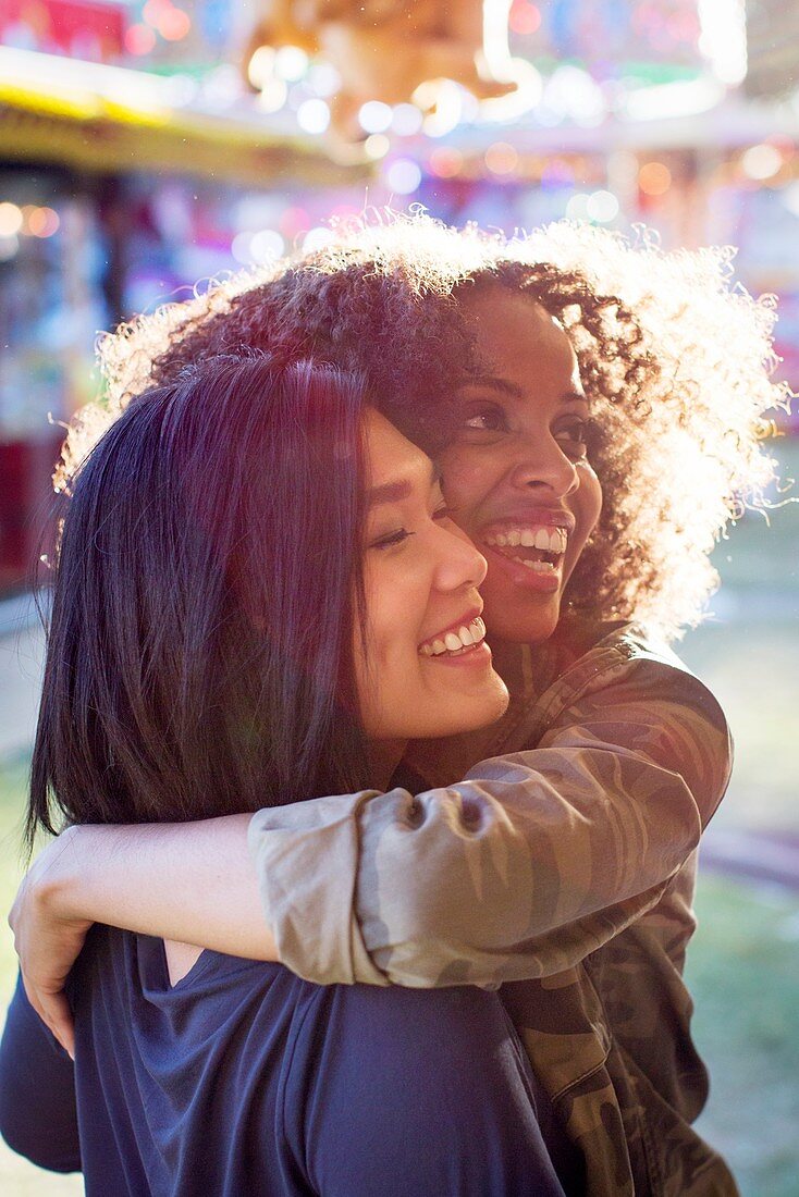 Women hugging and laughing in sunlight