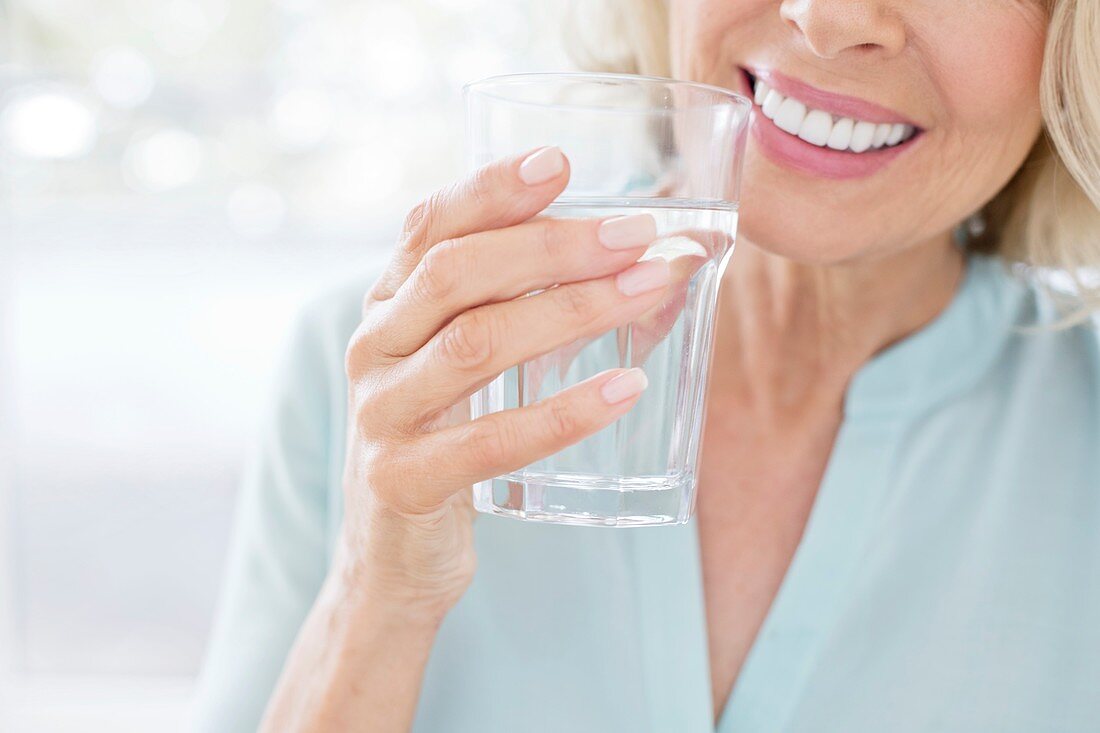 Mature woman smiling with glass of water