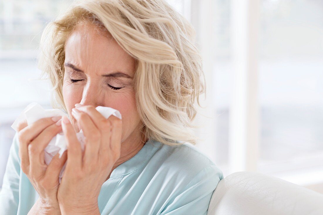 Mature woman blowing nose on tissue