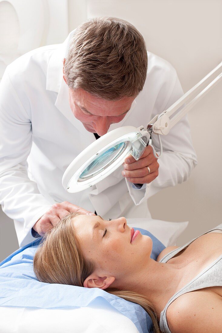 Doctor examining young woman's face