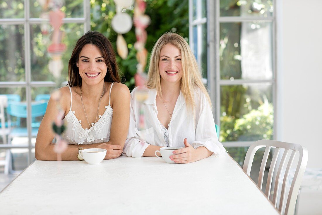 Women sitting at table with coffee, smiling