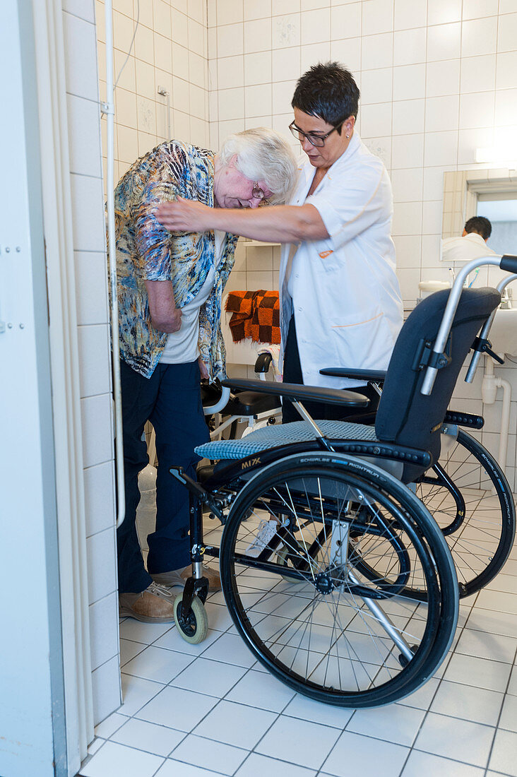 Nurse aiding an elderly woman to the toilet