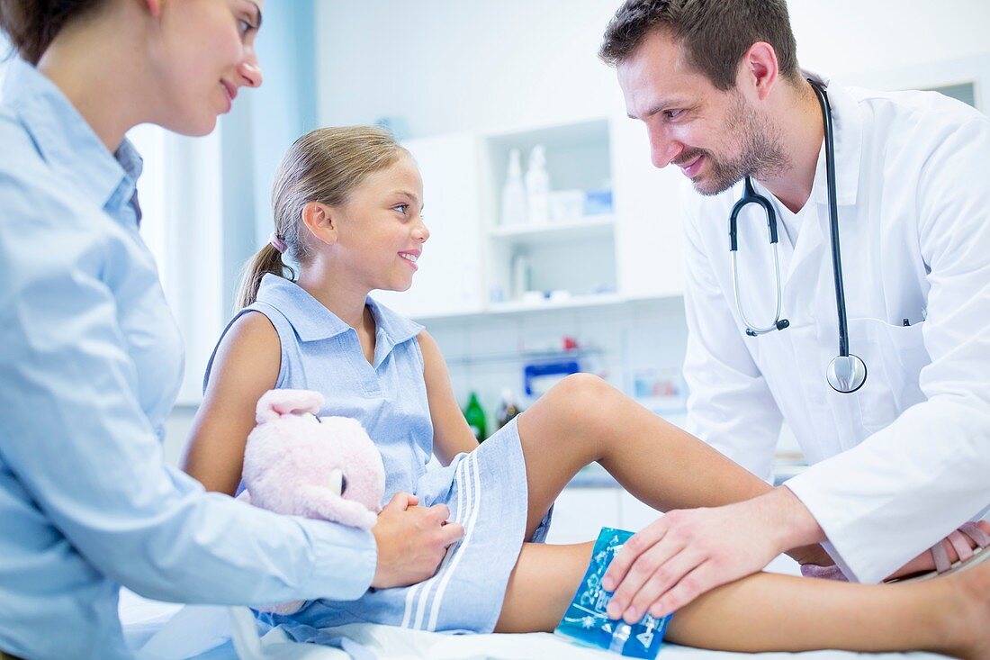 Doctor putting ice pack on girl's leg