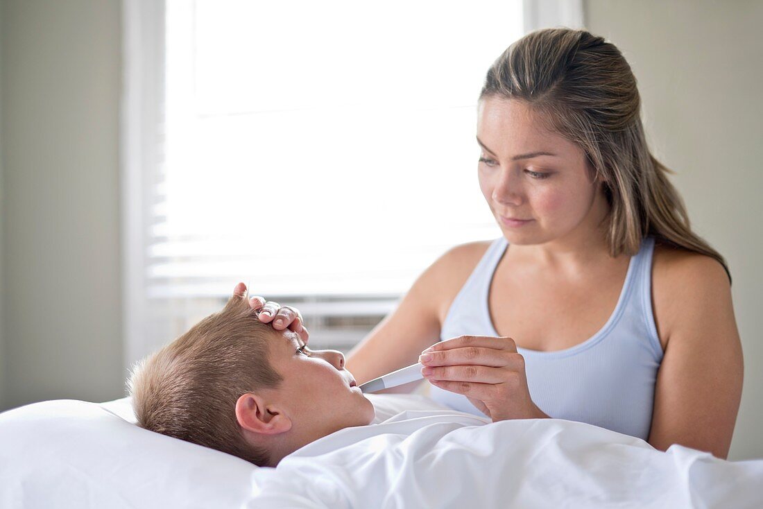 Mother taking son's temperature in bed