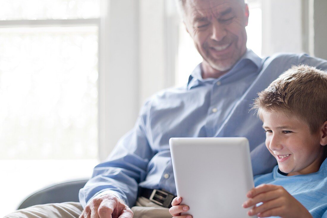 Boy using tablet with his grandfather