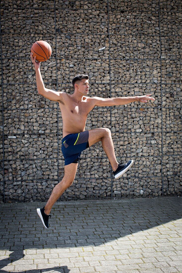 Young man jumping with basketball