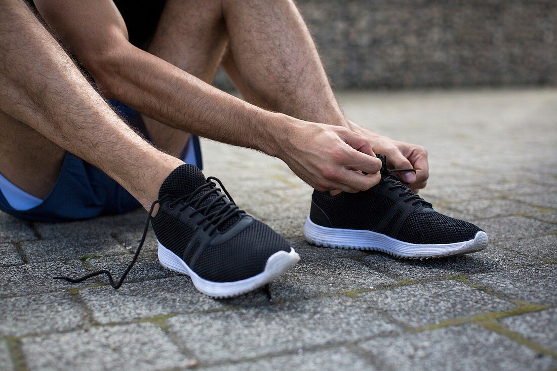 Man tying up shoelaces on trainers